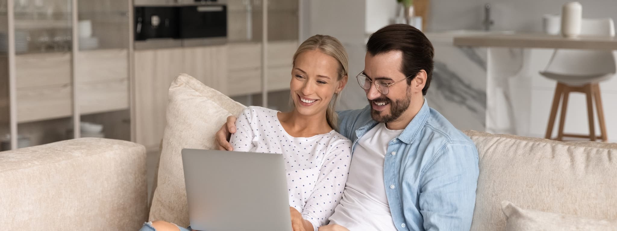 Couple sitting together on a couch sharing a laptop β the warmth and connection that therapy supports